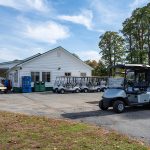 fleet of golf carts parked in lot next to building