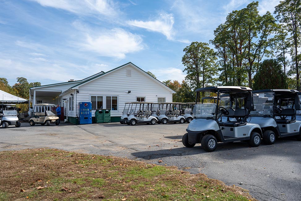 fleet of golf carts parked in lot next to building